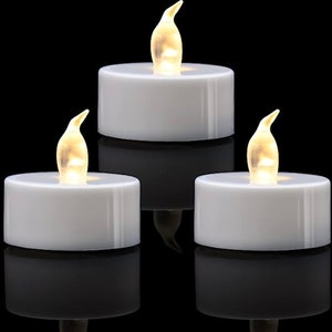 May include: Three white LED tea lights with a realistic flickering flame effect. The tea lights are in a dark background.