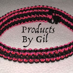 May include: A black and pink paracord strap with a black plastic clip. The strap is made of two strands of paracord, one black and one pink, woven together. The strap is about 1 inch wide and is about 40 inches long. The strap is a popular choice for carrying a variety of items, such as keys, wallets, and cell phones.