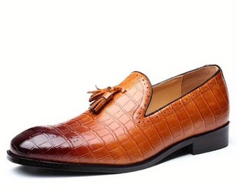 May include: Brown leather loafers with a crocodile pattern and a tassel detail. The shoes have a pointed toe and a low heel.