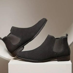 May include: A pair of black suede Chelsea boots with elastic side panels. The boots have a pointed toe and a low heel.