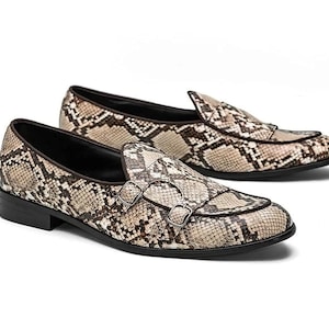 Peut inclure: Une paire de mocassins marrons et beiges à motif peau de serpent. Les mocassins ont un détail de boucle et une pointe pointue.