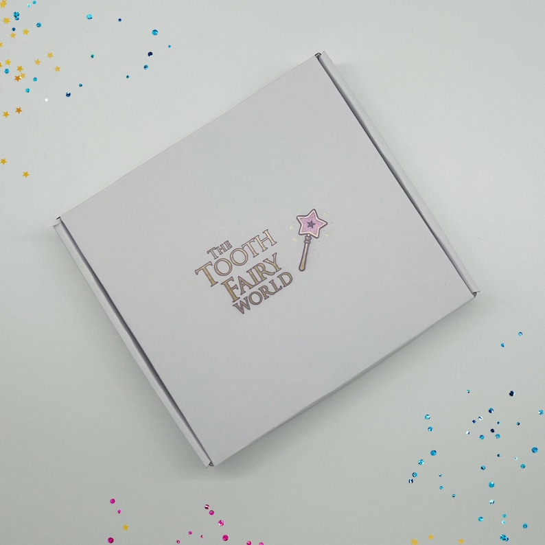 Peut inclure: Une bo&icirc;te blanche avec le texte "The Tooth Fairy World" et une &eacute;toile rose sur une baguette imprim&eacute;e sur le dessus.