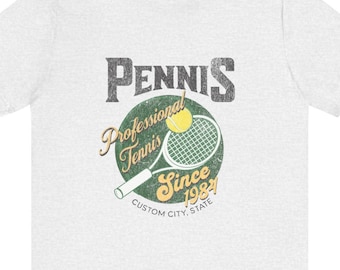 May include: A white t-shirt with a vintage-style graphic of a tennis racket and ball. The graphic says "Pennnis Professional Tennis Since 1984" and "Custom City, State".