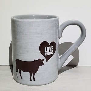 May include: Gray ceramic mug with a brown cow silhouette and a heart with the text "LOVE HERSHEY'S" on it.