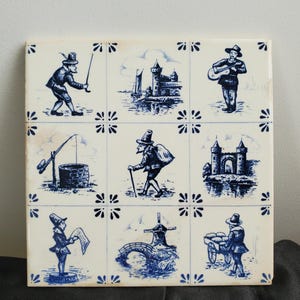 May include: Square ceramic tile with nine blue and white illustrations of Dutch scenes. Each square depicts a different scene, including figures fishing, castles, musicians, and windmills. The tile has a floral border design.