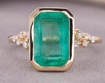 Anillo de compromiso con esmeralda natural, bisel octogonal y detalles de diamantes en oro amarillo.