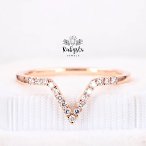 May include: A rose gold band ring with a V-shaped row of small diamonds. The ring is on a white background.