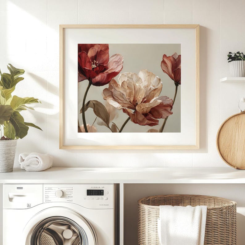 May include: A framed floral print featuring large, watercolor-style flowers in shades of red and peach. The artwork is set against a neutral background and framed in a light wood. The print is displayed above a white countertop.