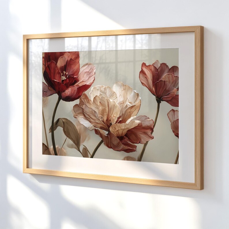 May include: A framed floral art print featuring a close-up of several large, stylized flowers in shades of red, peach, and cream. The artwork is set against a neutral background and framed in a light wood frame.