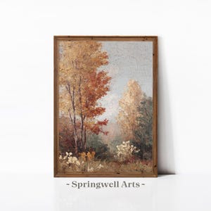 May include: A framed landscape painting depicting trees with autumnal colours of orange, yellow, and brown. The artwork has a textured finish and is set against a pale blue sky. The frame is wooden. The text "- Springwell Arts -" is at the bottom.