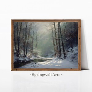 Op de afbeelding: Een landschapsschilderij in een bruine houten lijst met een besneeuwd bos, kale bomen, een kleine stromende beek en zacht licht dat door de takken valt. De tekst Springwell Arts staat onder het ingelijste kunstwerk afgedrukt.