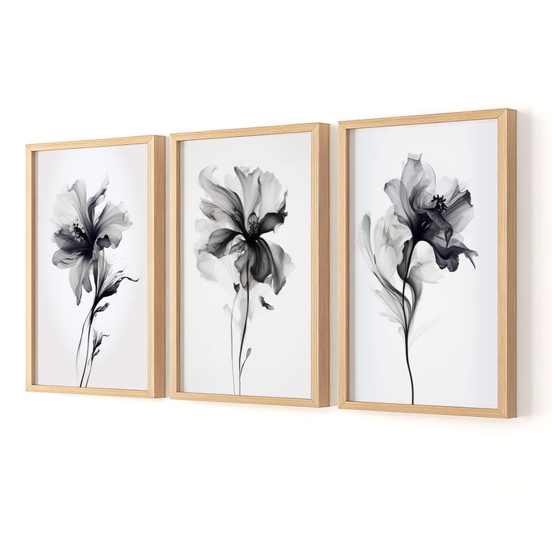 May include: Three framed floral art prints. Each print features a black and white image of a flower with delicate petals and stems. The frames are made of light-colored wood, and the background is white.