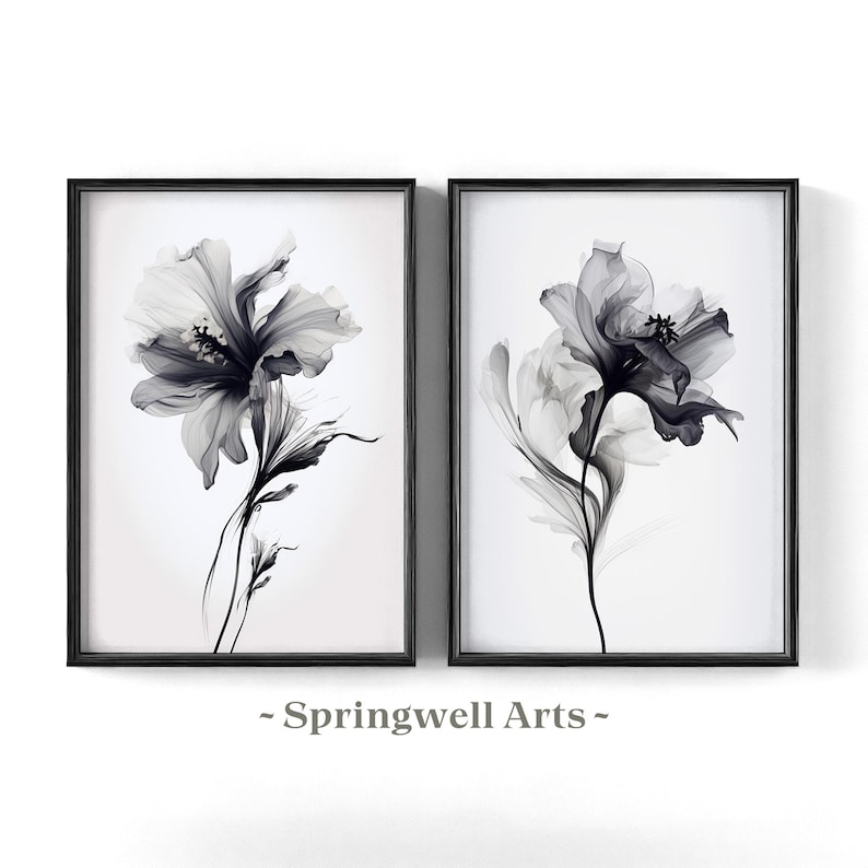 May include: Two framed floral art prints. Each print features a grayscale image of a flower with delicate petals and stems against a white background. The frames are black. The text "~ Springwell Arts ~" is at the bottom.