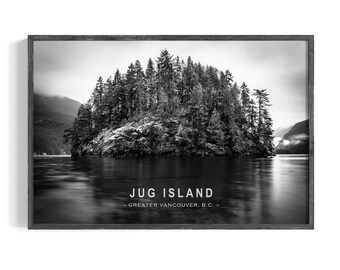 May include: Black and white framed print of Jug Island in Greater Vancouver, B.C. The island is covered in trees and surrounded by water. The print has a dark wooden frame.