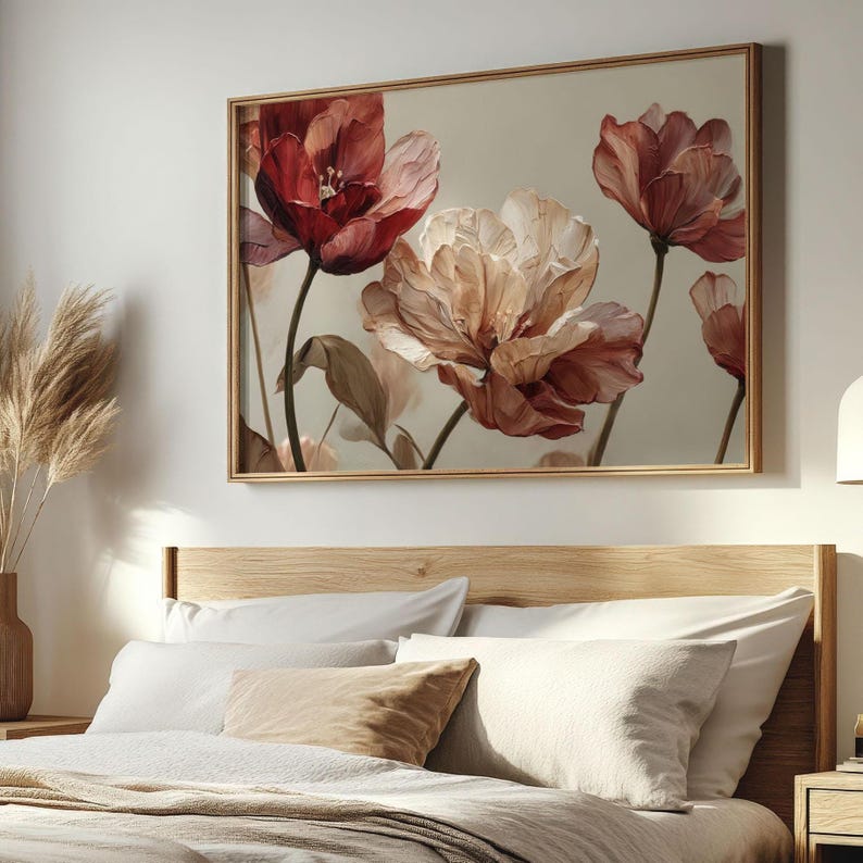 May include: A framed floral art print featuring large, stylized flowers in shades of red, peach, and cream against a neutral background. The artwork is displayed above a bed with white bedding and a wooden headboard, creating a serene bedroom aesthetic.