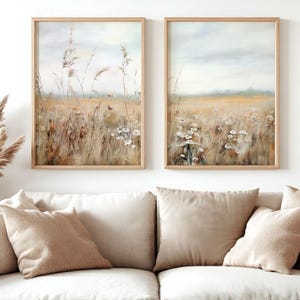 Può includere: Due dipinti di paesaggio incorniciati con una tavolozza di colori tenui. I dipinti raffigurano un campo di erba alta e fiori selvatici con un cielo nebbioso sullo sfondo.