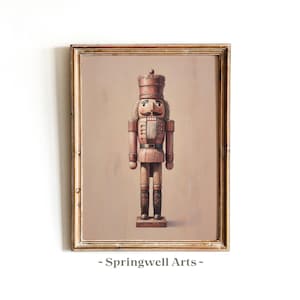 May include: A framed print of a wooden nutcracker soldier. The nutcracker is painted in shades of brown and tan, with black boots and a detailed face. The frame is gold. The text "- Springwell Arts -" is at the bottom.