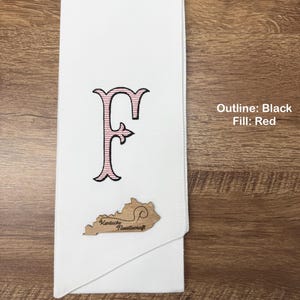 May include: White towel with an embroidered letter "F" in black outline and red fill. A wooden cutout of Kentucky with "Kentucky Needlecraft" is attached. The text "Outline: Black Fill: Red" is in the image.