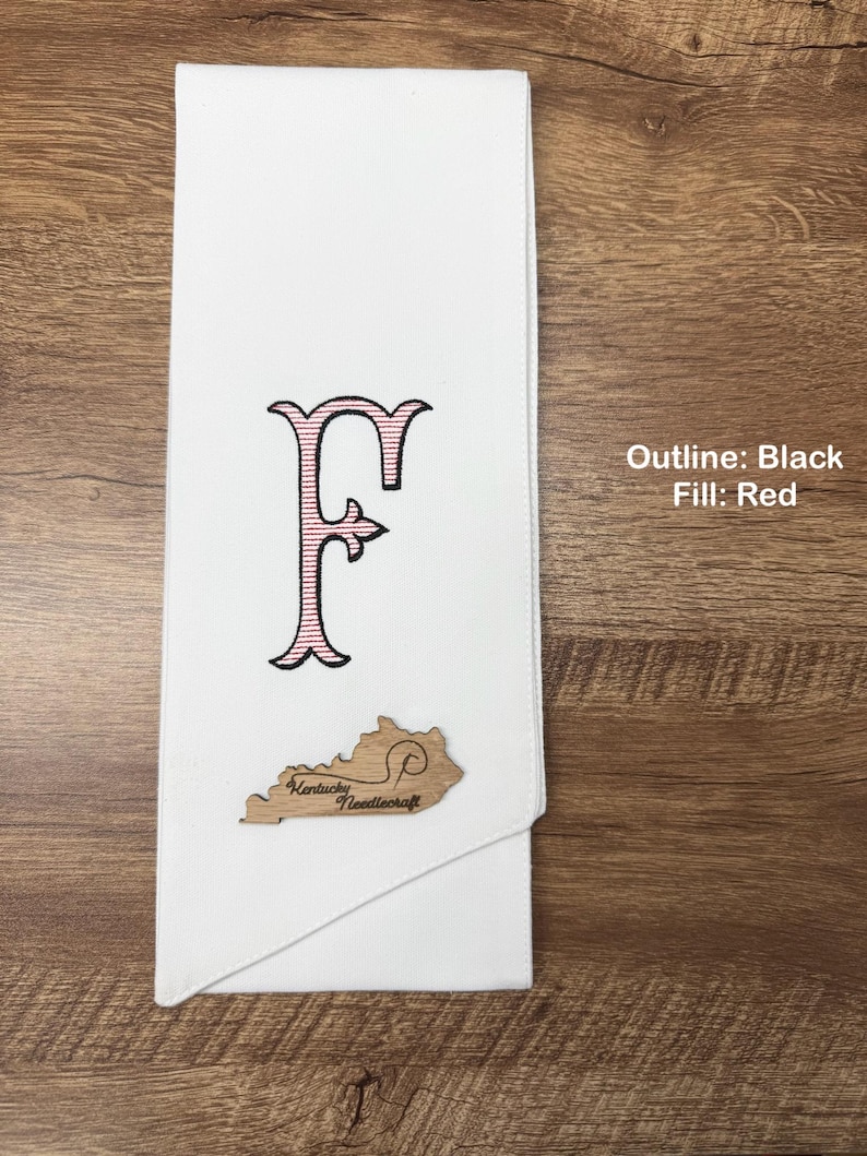 May include: White towel with an embroidered letter "F" in black outline and red fill. A wooden cutout of Kentucky with "Kentucky Needlecraft" is attached. The text "Outline: Black Fill: Red" is in the image.