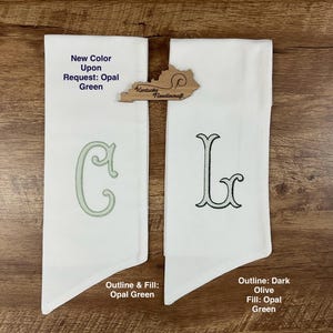 May include: Two white fabric items with embroidered letters, "C" and "L", in opal green and dark olive. The text "New Color Upon Request: Opal Green" is visible. A wooden Kentucky Needlecraft logo is also present.