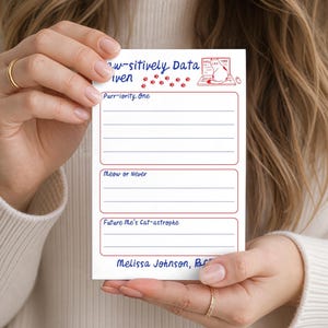May include: A white rectangular notepad featuring the blue text "Paw-sitively Data Driven" with red paw prints and a cat illustration. It includes three sections labeled "Purr-iority One," "Meaw or Never," and "Future Me's Cat-astrophe" with lines for writing.