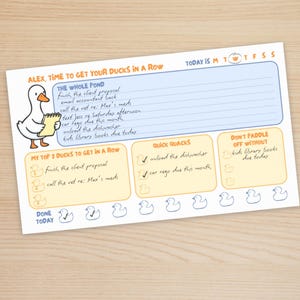 May include: A rectangular daily planner notepad featuring a white duck illustration and the text Alex, Time to Get Your Ducks in a Row. It includes sections labeled The Whole Pond, My Top 3 Ducks to Get in a Row, Quick Quacks, and Don't Paddle Off Without.