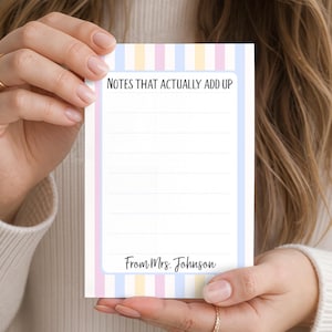 May include: A rectangular notepad featuring a vertical striped pattern in pastel blue, yellow, and pink. The top section displays the text "NOTES THAT ACTUALLY ADD UP" in black, followed by lined space for writing, and "From Mrs. Johnson" at the bottom.