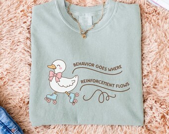 May include: A light green t-shirt with a cartoon duck wearing roller skates and the text "Behavior goes where reinforcement flows".