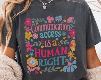May include: A dark gray t-shirt with a floral design and the text "Communication access is a human right".