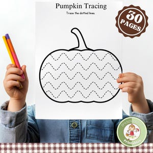 May include: A child holds a white paper with a pumpkin tracing activity. The paper has the text "Pumpkin Tracing" and "Trace the dotted lines." The image includes a brown sticker that says "30 PAGES" and a green sticker that says "Preschool Pop Printables."