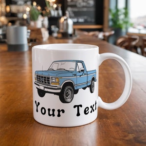 May include: White ceramic mug with a blue pickup truck illustration and the text "Your Text" printed on the front.