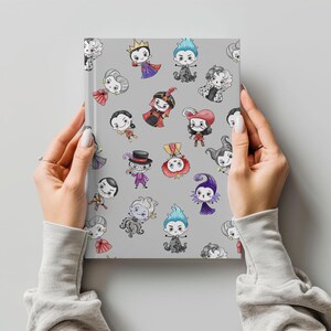 May include: A gray notebook featuring cartoon illustrations of various characters in colorful outfits. The notebook is held by hands with a light gray background.