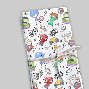 May include: A wrapped package featuring a white background with colorful illustrations of superheroes. The illustrations include characters like Spider-Man, Wolverine, and the Hulk, along with comic book sound effects. The package is tied with a natural twine.