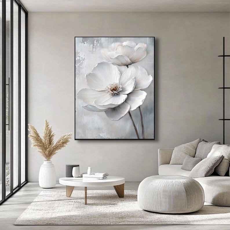 Puede incluir: Una gran obra de arte en lienzo enmarcada con dos grandes flores blancas texturizadas con centros marrones sobre un fondo gris claro y blanco. La obra de arte se exhibe en un sal&oacute;n moderno con tonos neutros y luz natural.