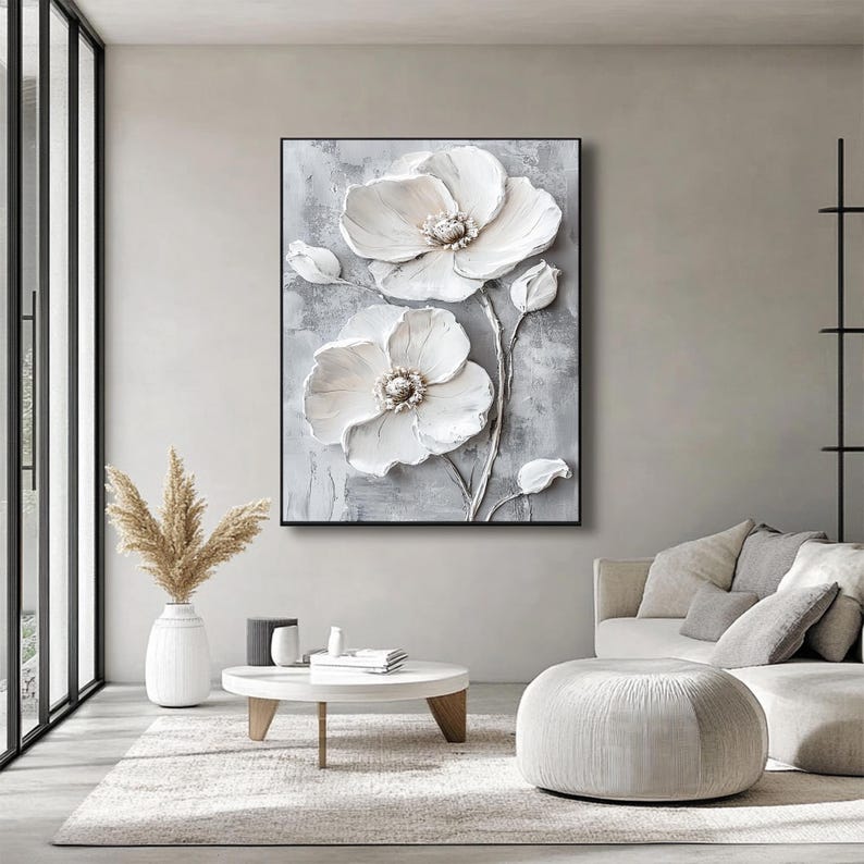 Puede incluir: Una obra de arte grande y enmarcada que presenta una representaci&oacute;n tridimensional texturizada de flores blancas sobre un fondo gris. Las flores tienen p&eacute;talos detallados y un n&uacute;cleo texturizado. La obra se exhibe en un sal&oacute;n moderno.