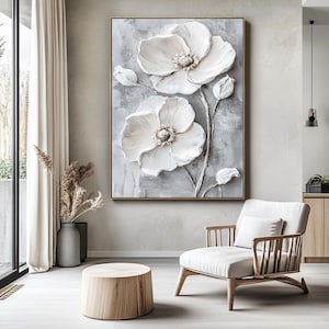 Puede incluir: Obra de arte enmarcada y texturizada que presenta dos grandes flores blancas tridimensionales con centros detallados y capullos sobre un fondo gris. La obra se exhibe en un sal&oacute;n moderno con una paleta de colores neutros.