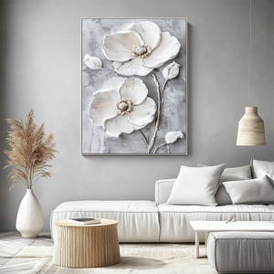 Puede incluir: Una obra de arte enmarcada que presenta un relieve 3D de flores blancas con p&eacute;talos texturizados y un marco plateado. La obra est&aacute; sobre un fondo gris, creando una est&eacute;tica moderna y elegante. Las flores son el punto focal de la obra.