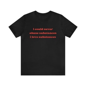 May include: Black t-shirt with the text "i could never abuse substances i love substances" in a red, sans-serif font. The shirt is a crew neck style and appears to be made of a soft material.