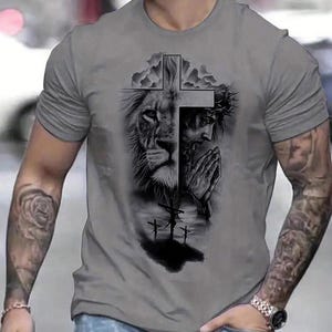 A man wearing a gray t-shirt with a graphic design depicting a lion and a cross.