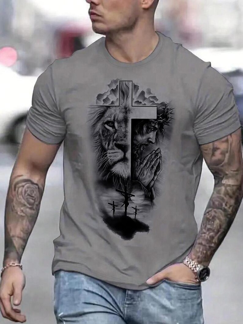 A man wearing a gray t-shirt with a graphic design depicting a lion and a cross.