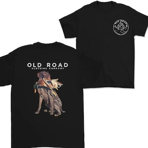 May include: Black t-shirts with the "OLD ROAD CLOTHING COMPANY" logo. One shirt features a graphic of a dog with a duck in its mouth. The other shirt has a mountain and tree design.