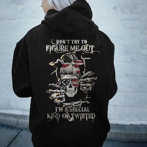 May include: Black hooded sweatshirt with a graphic on the back. The graphic features a skull wearing sunglasses and a headband with the American flag design. The text reads "DON'T TRY TO FIGURE ME OUT" and "I'M A SPECIAL KIND OF TWISTED."