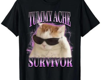 May include: Black t-shirt featuring a cat wearing sunglasses with the text "TUMMY ACHE SURVIVOR" in a purple, retro font. The cat is white and orange, with a lightning bolt design behind it.