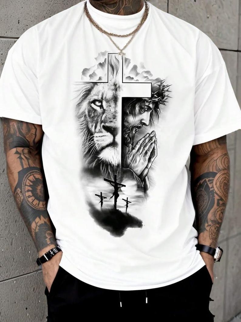 A white t-shirt with a graphic design depicting a lion and a praying man, along with a cross and clouds.