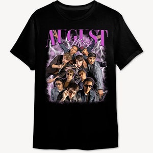 May include: Black t-shirt with a graphic print of a group of young men in front of a purple lightning bolt design. The text "AUGUST MOON" is printed in purple above the graphic.