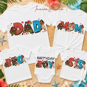 May include: A collection of white t-shirts and a baby bodysuit featuring colorful graphic text designs. The shirts display the words DAD, MOM, BRO, and SIS, while the bodysuit says BIRTHDAY BOY. Each letter incorporates Moana characters.