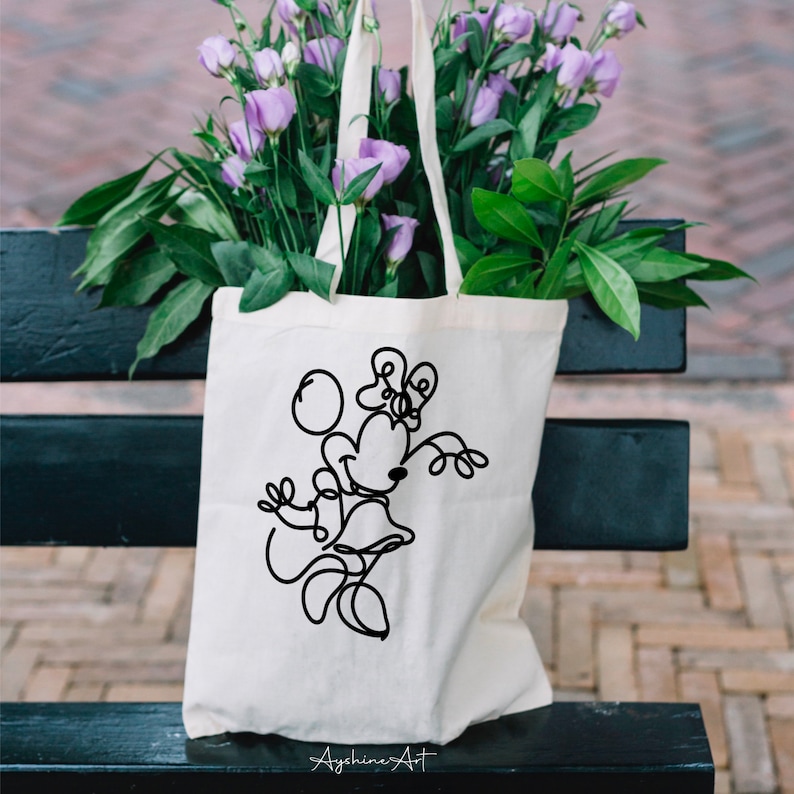 May include: White tote bag with a black line drawing of Minnie Mouse playing with a ball. The text "Ayshine's Art" is at the bottom of the bag.