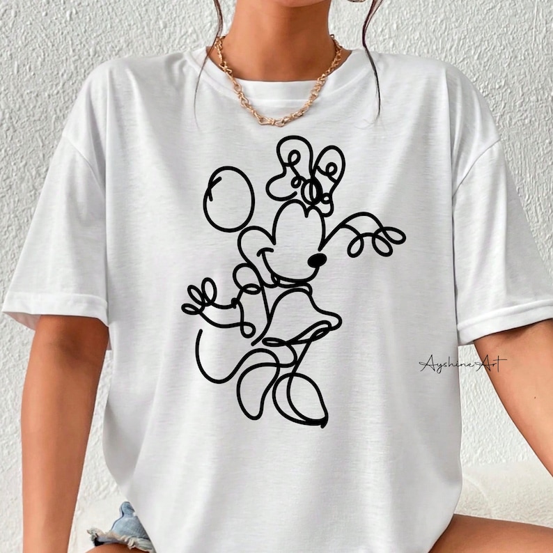 May include: White t-shirt with a black line drawing of Minnie Mouse. The drawing shows Minnie Mouse with her signature bow and holding a ball. The text "Ayshine's Art" is in the bottom right corner of the shirt.