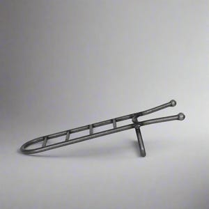 May include: A metal wine bottle holder shaped like a ladder with rounded ends. The holder is made from a single piece of metal and has a rustic, industrial look.