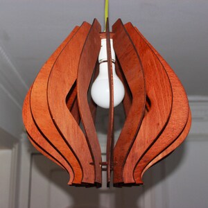 May include: A wooden pendant light fixture with a modern design. The light fixture is made of multiple layers of wood that are curved and interlocked to create a unique shape. The light fixture is illuminated by a single light bulb.